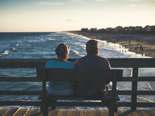 Couple sitting on a bench by the beach